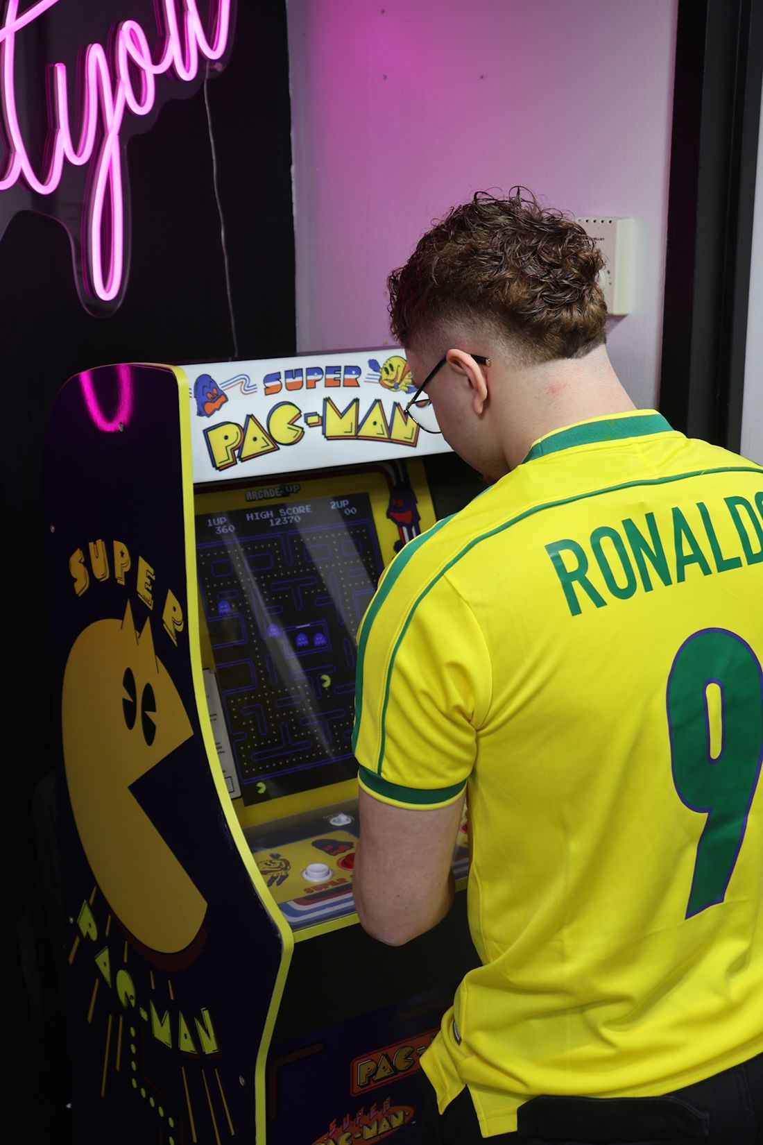 Player in a yellow Brazil Ronaldo 9 jersey at a Pac-Man arcade